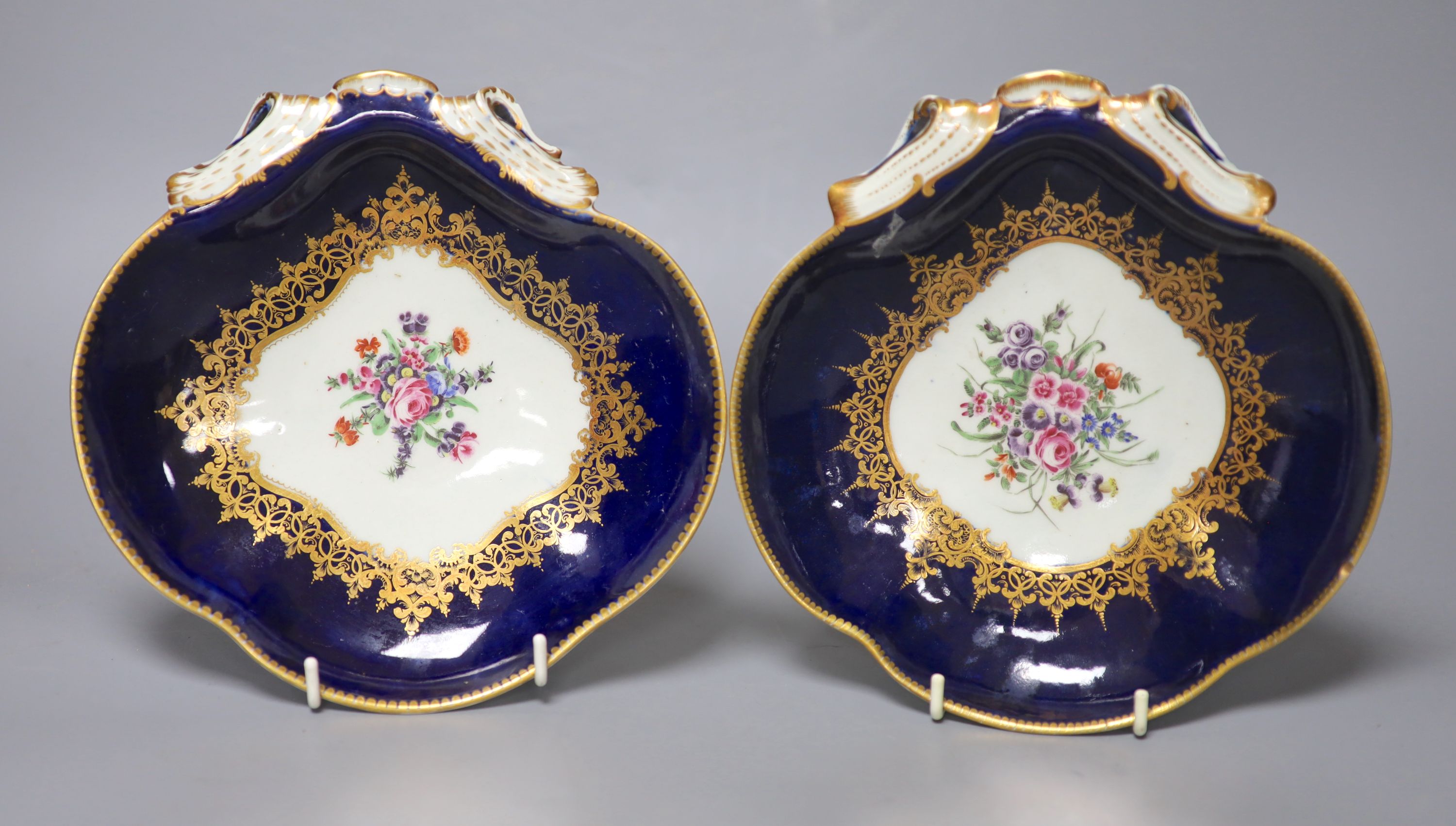 A pair of 18th century Worcester shell shaped dishes painted with flowers surrounded by rich gilding, length 19.5cm